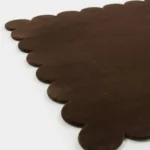Close up detail of the Cocoa Earth rug showing the deep brown color and soft wool texture of the scalloped border.