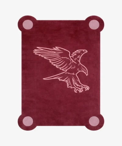 Top down view of the Ember Crest rug featuring a deep maroon wool background with a stylized light pink line art illustration of an eagle in flight, framed by decorative circular corner accents.
