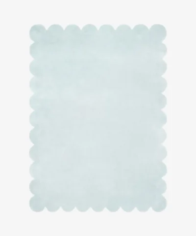 Top down flat lay of the Glacier Haze hand tufted rug featuring a calming solid ice blue color and decorative wavy edges isolated on a white background.