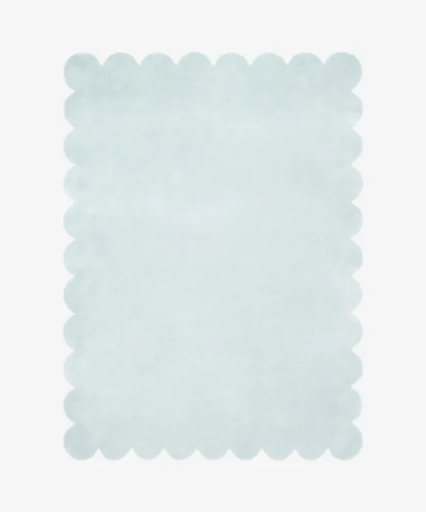 Top down flat lay of the Glacier Haze hand tufted rug featuring a calming solid ice blue color and decorative wavy edges isolated on a white background.