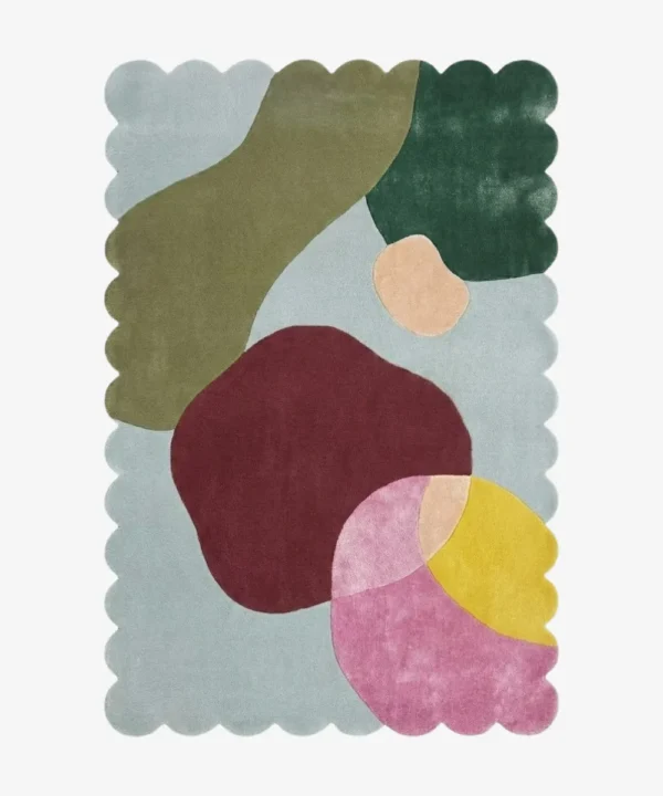 Top down view of the Pebble Parade rug against a white background, featuring large, organic, pebble-like abstract shapes in shades of olive green, dark green, deep burgundy, pink, yellow, and peach on a light blue background, framed by a continuous light blue scalloped border.