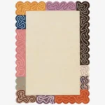 Top down view of the Soft Frame rug featuring a large neutral cream wool center framed by a playful multicolored border of striped blocks in pink, orange, brown, and purple, finished with custom scalloped edges.