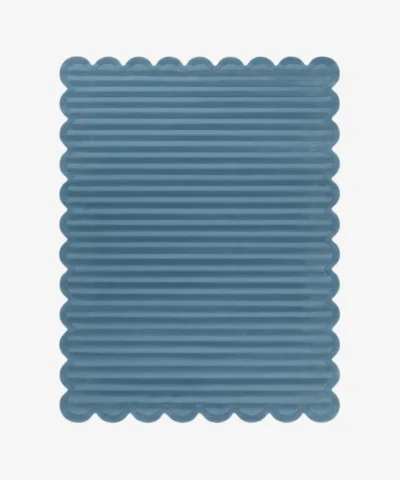 Top down view of the Still Tides rug featuring a solid dusty blue color with horizontal carved textures and decorative scalloped edges.