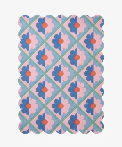 Top down view of the Sugar Trellis rug featuring a retro diamond grid pattern with pink and blue floral motifs and scalloped edges on a hand tufted wool background.