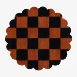 A top-down, flat lay view of the round Cinder Form rug against a grey background, showcasing its complete circular shape, abstract charcoal grey patterns over a cream field, and a continuous charcoal scalloped edge.