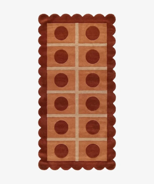 Top-down view of the rectangular Cocoa Ridge runner rug, featuring a retro-inspired grid of light peach squares containing dark cocoa brown circles, all framed by a thick terracotta scalloped border and intersecting cream lines.