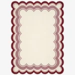 Top-down view of the rectangular Elvare Bloom rug, featuring a large cream center framed by concentric, scalloped border layers in soft pink, lavender, and a deep plum outer edge.
