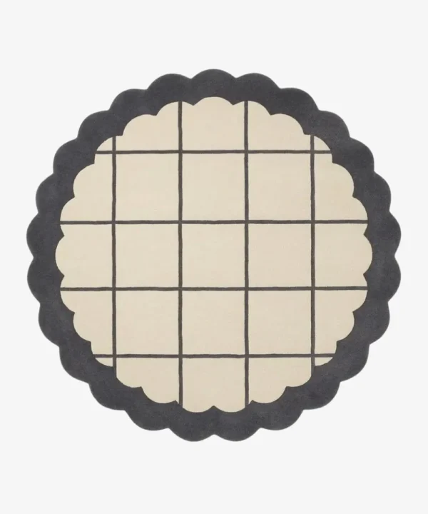 Top-down view of the circular Orbital Grid rug featuring a soft cream center with a classic dark grey windowpane grid, framed by a thick dark grey scalloped border.