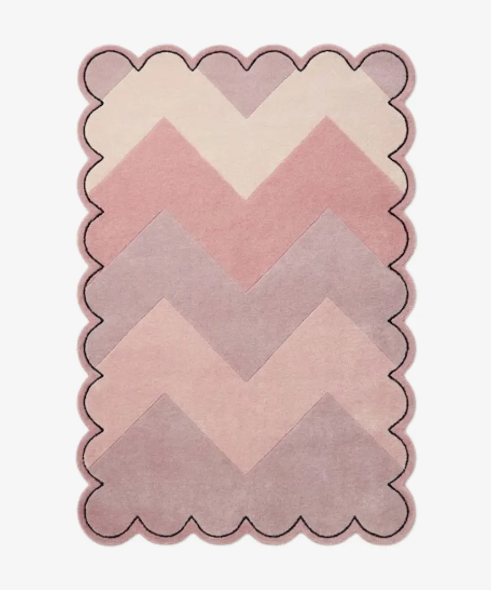 Top-down view of the Rose Chevron rug featuring a gradient zigzag pattern in shades of cream, soft blush, rose, and mauve, framed by a continuous scalloped border with a thin black outline.