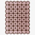 Top-down view of the rectangular Roselle Lattice rug, featuring a soft pink base with a dark brown grid pattern, a central floral motif in each square, and a matching continuous brown scalloped border.