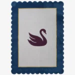 Top-down view of the Swan Crest hand-tufted wool rug featuring a central dark purple swan silhouette on a light grey rectangular field, framed by a thin gold line and a bold navy blue scalloped border.
