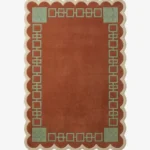 Top-down view of the rectangular Terrain Frame rug, featuring a solid rust orange center surrounded by a sage green geometric line border and framed by a continuous cream scalloped edge.