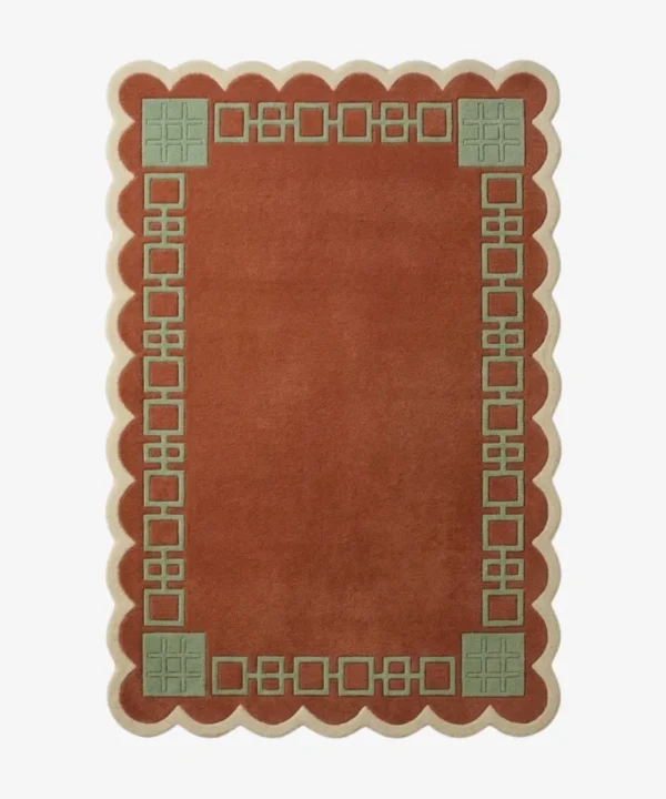 Top-down view of the rectangular Terrain Frame rug, featuring a solid rust orange center surrounded by a sage green geometric line border and framed by a continuous cream scalloped edge.