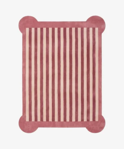 A top-down, flat view of the Rose Candy Stripe Scallop Rug on a clean white background. The tufted rectangular rug features vertical dusty rose and cream stripes, finished with a solid rose-colored border and unique rounded protruding corners.