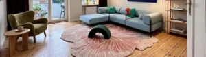 Wide view of a modern sunlit living room featuring a custom wavy green hand-tufted rug on a wooden floor, serving as the header image for the blog post 5 reasons hand tufted rugs are worth the investment.