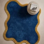 High-angle overhead shot of the wavy Indigo Tide rug in a minimalist room setting, demonstrating its organic fluid shape and bold color blocking.
