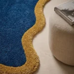 Close-up angled view of the Indigo Tide rug, highlighting the dense hand-tufted pile texture and clean color transition between the blue and mustard yellow sections.