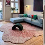 Large Rose Reverie rug in a living room setting with a light blue sofa and a dark green arch accent piece, showcasing its expansive, organic flower shape.