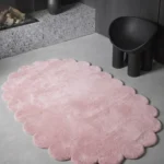 Oval Rosy Mellow Pink Scalloped rug styled in a minimalist room with a black accent chair, highlighting its soft, inviting color.