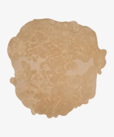 Isolated top-down view of the sand bloom rug on a white background, highlighting its unique, freeform organic shape and monochromatic beige color.