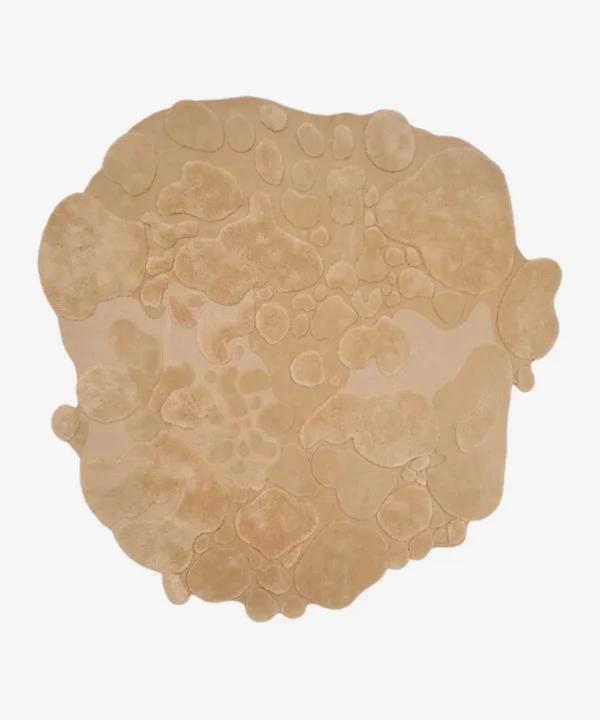 Isolated top-down view of the sand bloom rug on a white background, highlighting its unique, freeform organic shape and monochromatic beige color.