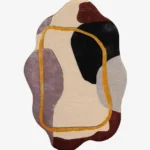 A flat, top-down view of the Terra Frame Scallop Rug isolated on a clean white background. The hand-tufted rug features an organic, wavy silhouette filled with abstract color blocks of black, grey, mauve, and deep red on a cream base, all visually connected by a continuous golden-yellow line forming a modern frame.