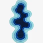 Full top-down product isolated shot of the uniquely shaped Aqualoom accent rug, featuring an organic fluid silhouette with concentric wavy bands of aqua, sky blue, royal blue, and a deep navy core.