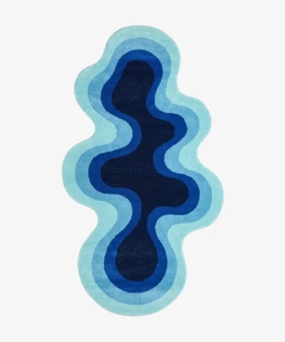 Full top-down product isolated shot of the uniquely shaped Aqualoom accent rug, featuring an organic fluid silhouette with concentric wavy bands of aqua, sky blue, royal blue, and a deep navy core.