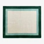 Full top-down product isolated shot of the cream, light teal, and dark green Avelis border rug.