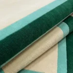 Close-up macro photograph highlighting the plush wool texture and layered green and cream border detail of the Avelis rug.