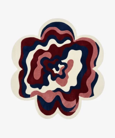 An overhead studio shot of a flower-shaped Bloom Wave area rug featuring wavy concentric layers of navy, burgundy, and cream.