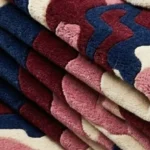 A close-up macro photograph showing the high-quality, plush pile texture and color transitions of the folded Bloom Wave rug.