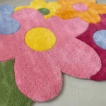 Close-up top angle perspective highlighting the clean hand-tufted pile divisions, carved petal outlines, and premium texture of the pink and yellow elements on the Bloomtopia rug.