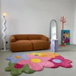 Wide perspective interior lifestyle shot of the multi-colored Bloomtopia floral rug styled on a gray concrete floor in front of a modern brown plush sofa.