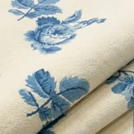 Close-up macro photograph highlighting the premium hand-tufted pile density, delicate leaf carving lines, and crisp two-tone blue color blocks of the folded Bluevine Bloom textile rug.