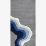 Full top-down product isolated shot of the rectangular Coastal Meridian area rug, featuring an intricate carved topographic wave design on a medium grey field transitioning into fluid abstract ocean contours of navy blue, royal blue, lavender, light teal, and cream.