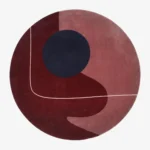 Full top-down product isolated shot of the round Eclipse area rug featuring abstract geometric blocks of burgundy, mauve, and a dark navy circle.