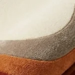 Close-up macro photograph highlighting the premium wool yarn density, plush material pile loops, and clean color layer tracking of the folded Elio Bend custom-shaped rug.
