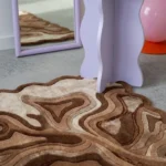 Detail close-up view of the Ember Terrain scalloped rug featuring a textured earth-tone topographical line design.