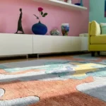 Low angle floor-level perspective showcasing the rich clay terracottas, muted aquas, and hand-carved design depth of the Estuary area rug.