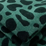 Close-up macro photograph highlighting the premium hand-tufted material pile and thick, dense loop texture of the folded green and black Fernfall rug.