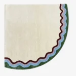 Full top-down product isolated shot of the uniquely shaped Garden Wave corner accent rug featuring a cream base with multi-colored wavy outer borders in green, purple, and burgundy tones.