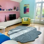 Overhead interior lifestyle shot of the hand-tufted blue Glacier Terrain topographical rug styled in a modern living room with colorful walls.