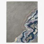 Full top-down product isolated shot of the rectangular Gray Meridian area rug, featuring an intricate carved topographic map design on a medium grey field that transitions into fluid abstract waves of deep blue, purple, teal, and cream.