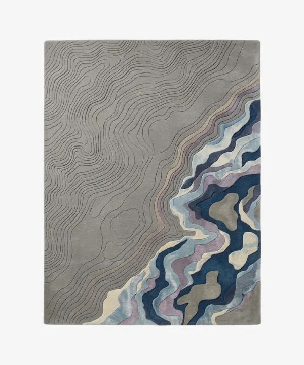 Full top-down product isolated shot of the rectangular Gray Meridian area rug, featuring an intricate carved topographic map design on a medium grey field that transitions into fluid abstract waves of deep blue, purple, teal, and cream.