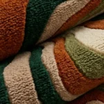 Close-up macro photograph highlighting the premium thick wool material texture and dense multi-level loop pile of the folded Groovy rug.