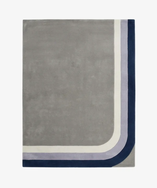 Full top-down product isolated shot of the rectangular Halo Verge area rug, featuring a large minimalist grey field bordered by retro mid-century curved corner bands in cream, lavender purple, and deep navy blue.