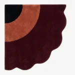 Full top-down product isolated shot of the uniquely shaped Harvest Moon scalloped corner rug featuring black, terracotta, and burgundy tones.