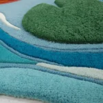 Close-up macro photograph highlighting the premium hand-tufted wool material texture and dense pile construction of the lily pad and wavy water segments on the Japanese Koi Fish Garden rug.