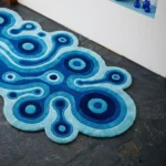Close-up top angle perspective showcasing the dense hand-tufted pile depth, unique wavy silhouette edges, and clean geometric linework of the Lagoon Loop blue runner rug.